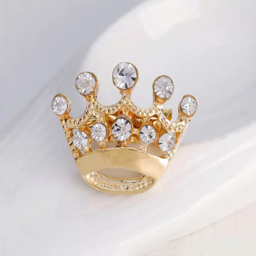 Gold crown-shaped ring with crystals on a light background