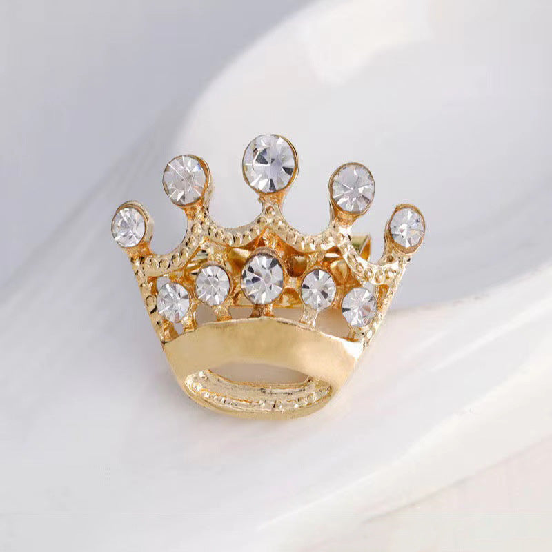 Gold crown-shaped ring with crystals on a light background