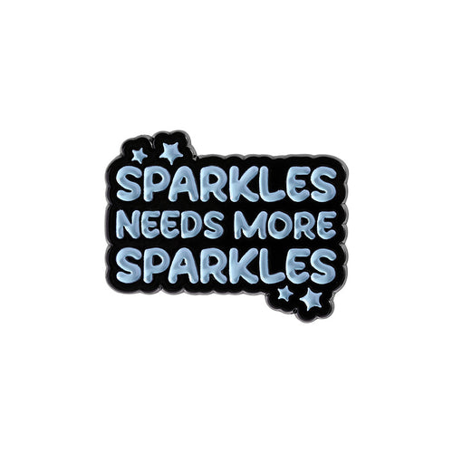 Enamel pin with 'Sparkles Needs More Sparkles' text on a white background