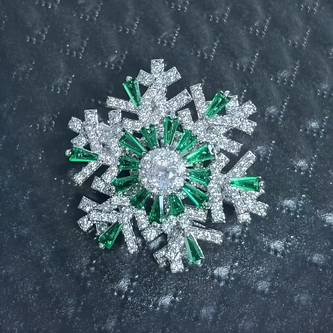 Snowflake-shaped brooch with green and clear gemstones on a dark textured background