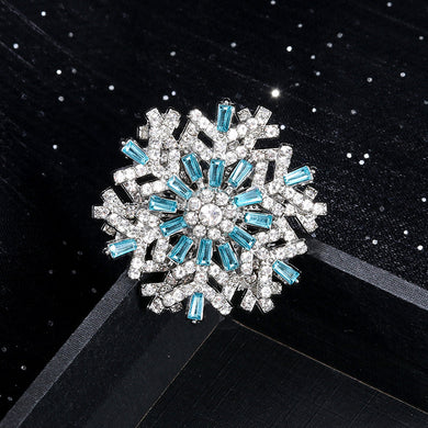 Snowflake-shaped brooch with blue and clear gemstones on a black background