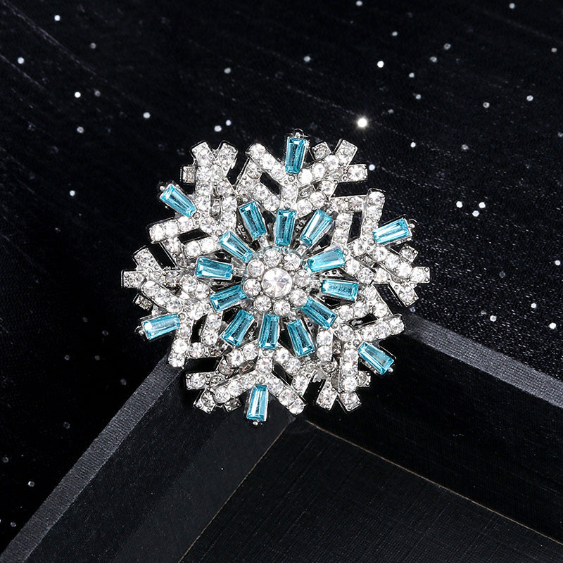 Snowflake-shaped brooch with blue and clear gemstones on a black background
