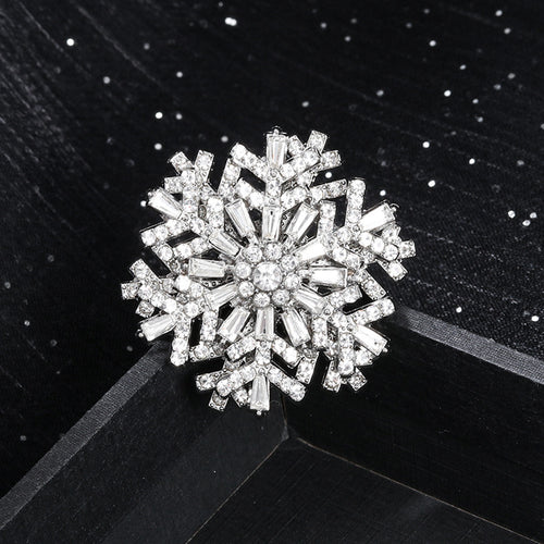 Silver snowflake-shaped brooch on a black background