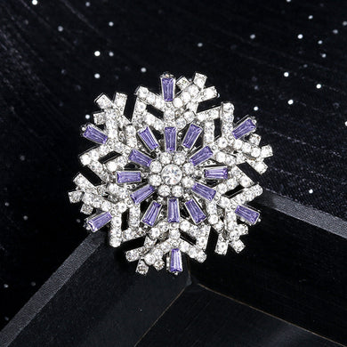 Snowflake-shaped brooch with purple and clear gemstones on a black background