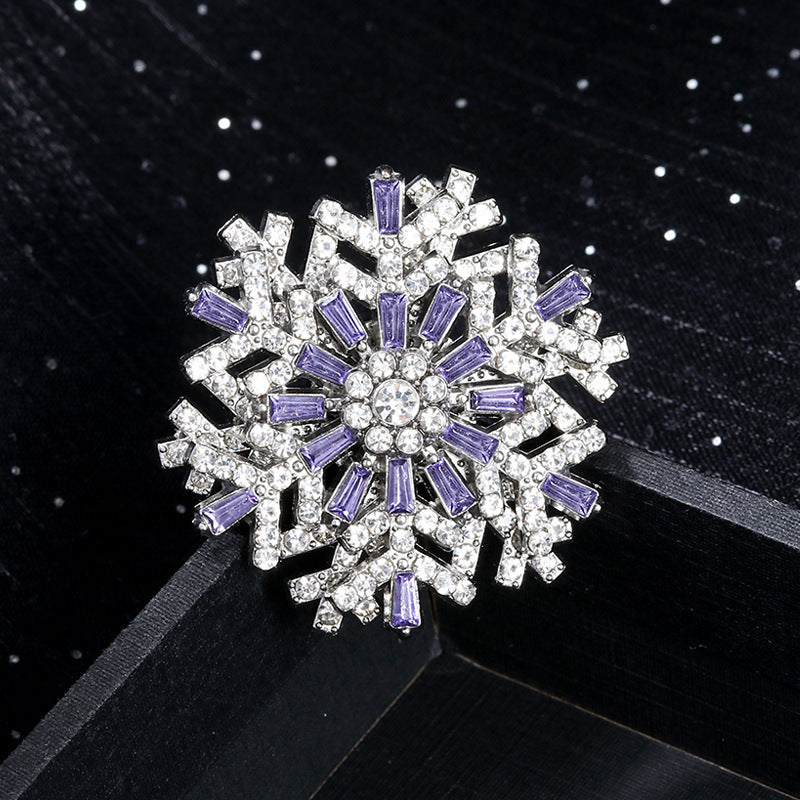Snowflake-shaped brooch with purple and clear gemstones on a black background