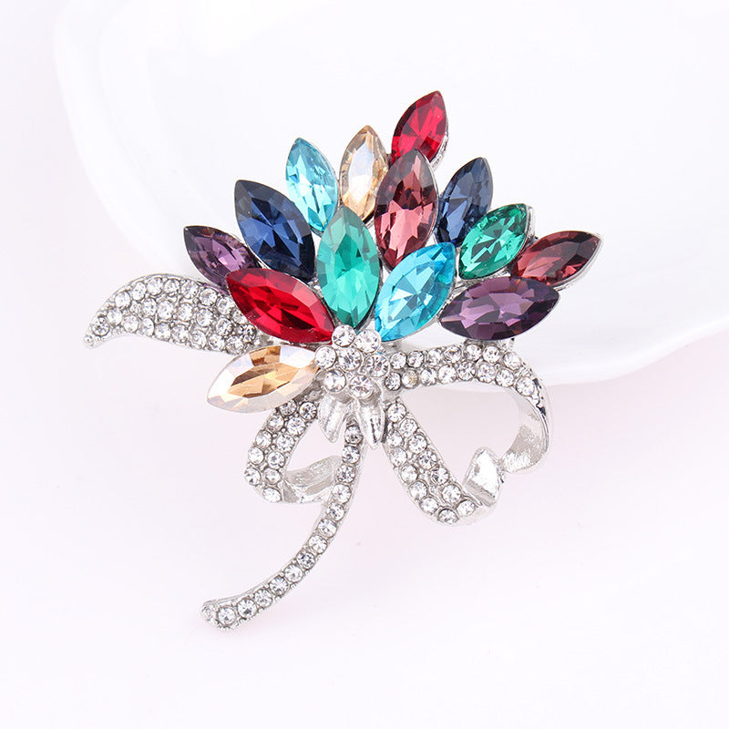 Multicolored gemstone brooch with a silver bow on a white background