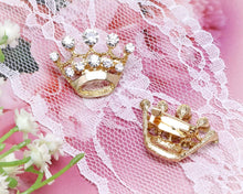 Load image into Gallery viewer, Gold crown-shaped jewelry on a pink lace background with white flowers.