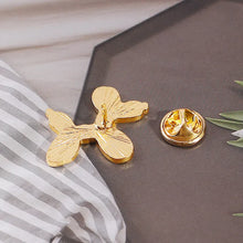 Load image into Gallery viewer, Gold butterfly-shaped earring on a dark surface with a striped fabric background