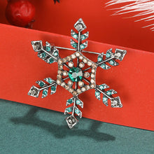 Load image into Gallery viewer, Decorative snowflake brooch with gemstones on a red and green background