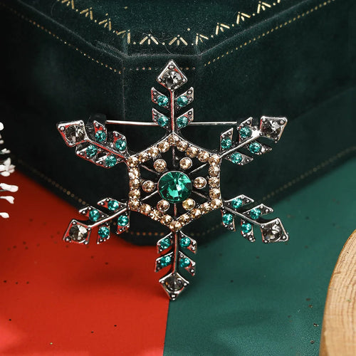 Decorative snowflake brooch with gemstones on a green and red background