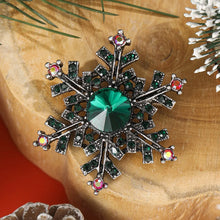 Load image into Gallery viewer, Decorative snowflake brooch with gemstones on a wooden surface