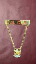 Load image into Gallery viewer, Gold chain with a badge featuring &#39;I.S.C.A.&#39; on a brown background