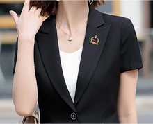 Load image into Gallery viewer, Person wearing a black blazer with a brooch and white shirt, blurred background